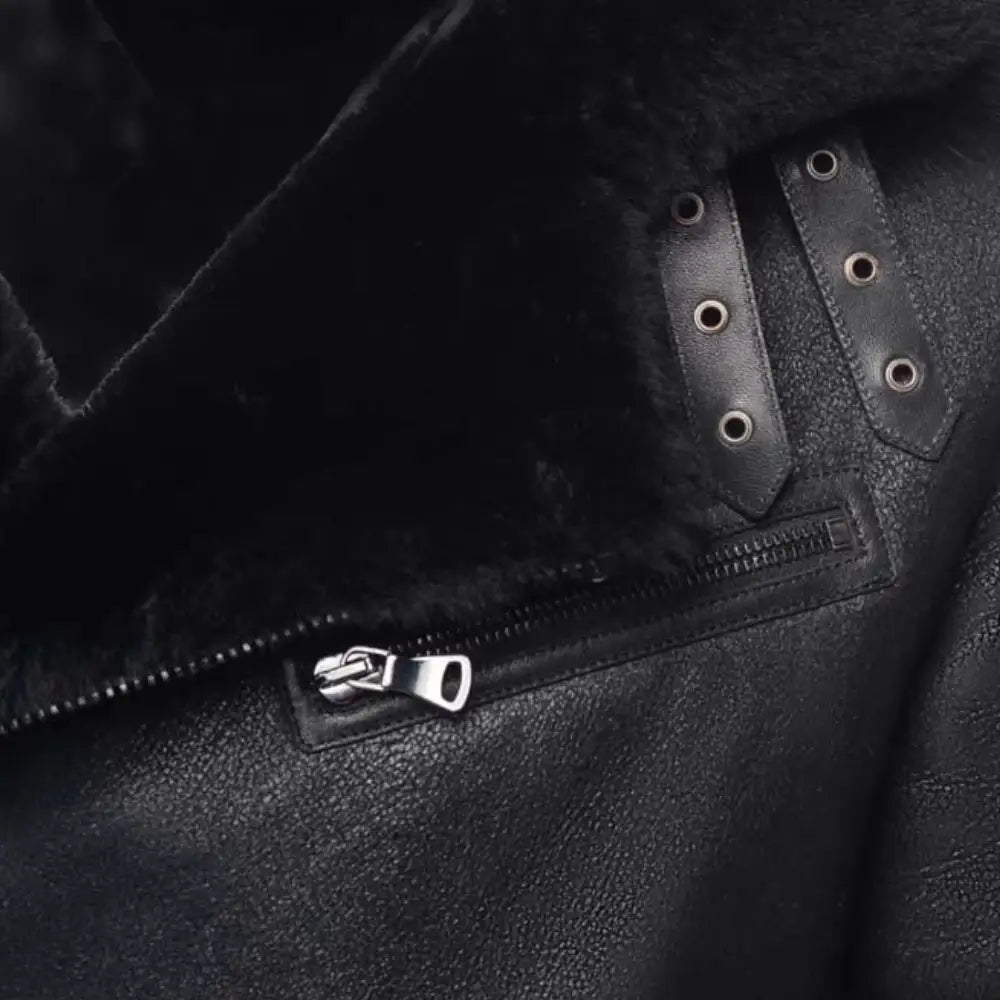 Close-up of a black leather jacket with a brand logo on the chest pocket.