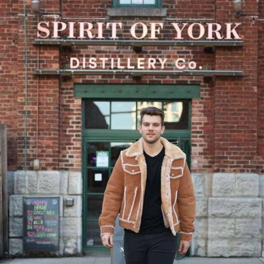 Man in a brown jacket standing in front of 'Spirit of York Distillery Co.'