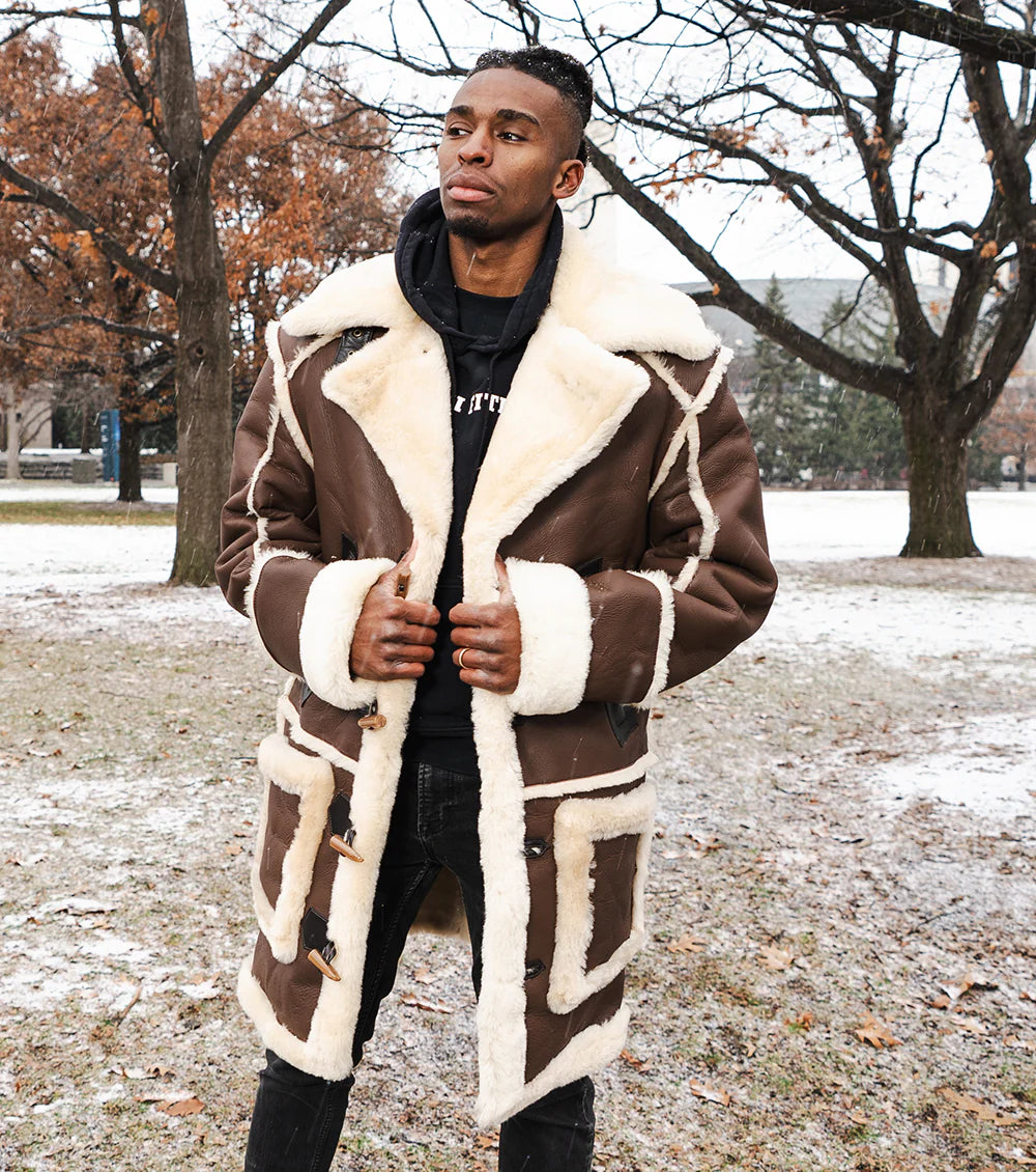 Man wearing a brown and white shearling coat in a snowy park setting