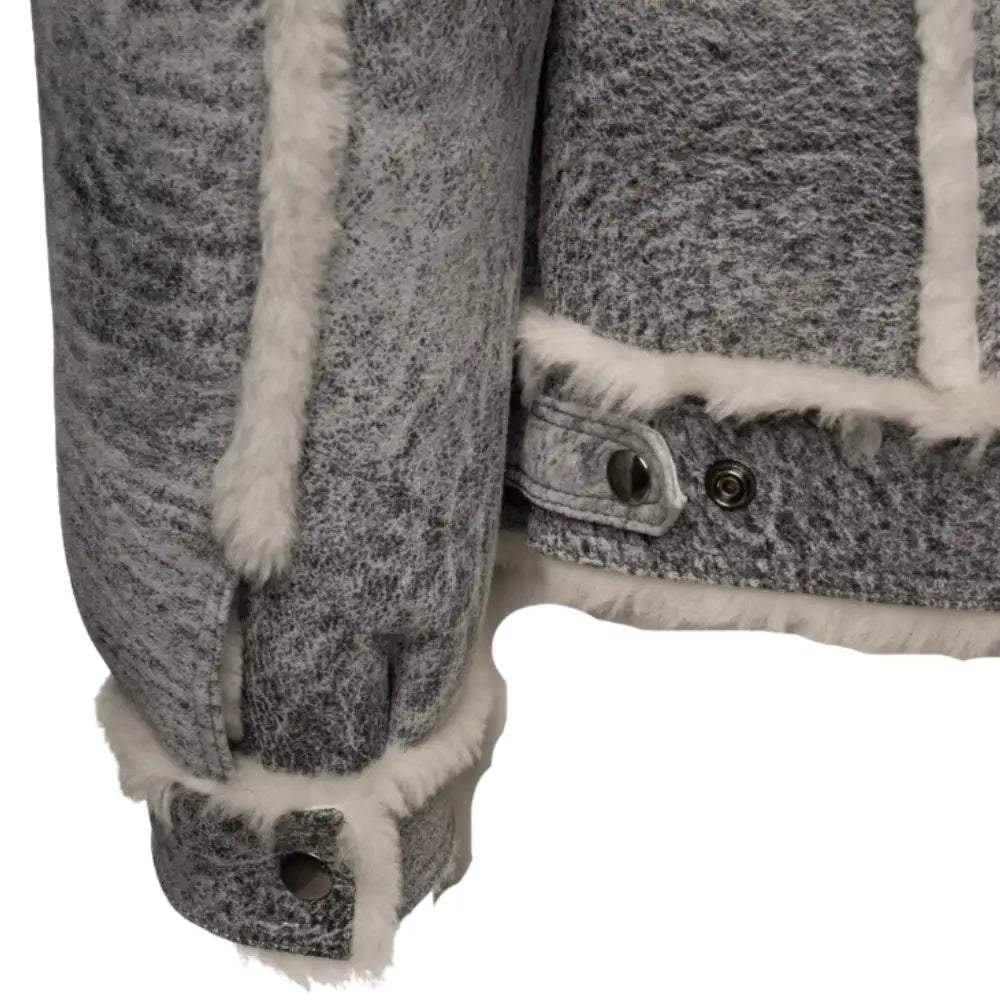 Close-up view of the sleeve cuff of Aiden's Distressed Grey Shearling Trucker Jacket, showcasing the white shearling lining and button detailing on the cuff. The fabric has a rugged, distressed grey texture with soft faux fur accents.