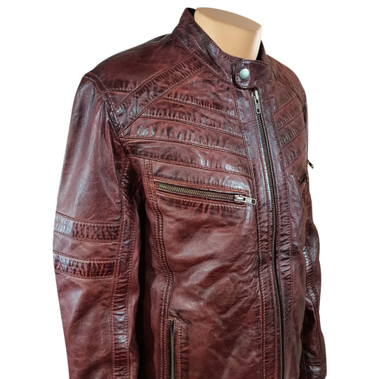 Close-up of the snap-tab mandarin collar and quilted shoulder padding on Charley Ellwood’s burnished burgundy moto jacket, white background.