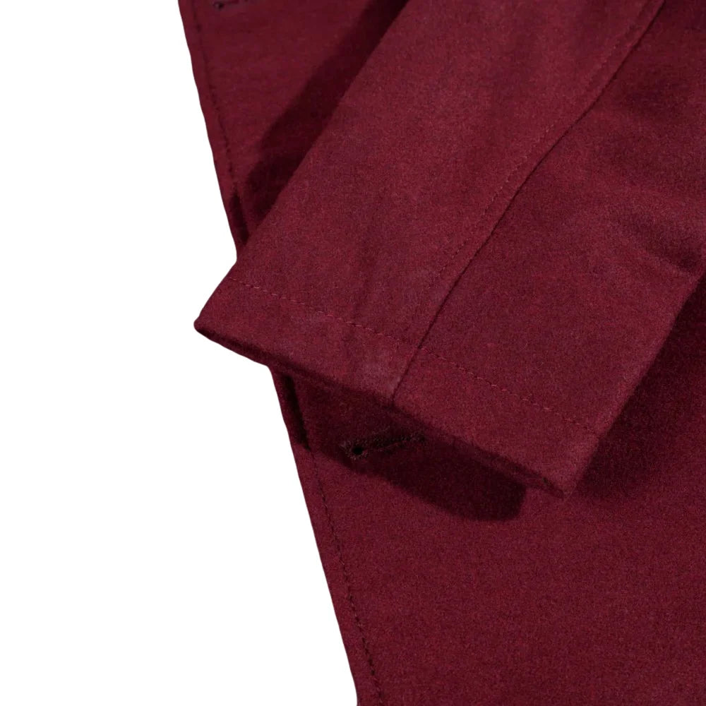 Close-up of a burgundy wool overcoat sleeve with a white background