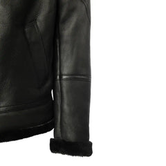 Side profile of the black bomber shearling jacket, highlighting its smooth leather design and ribbed knit cuffs that create a comfortable, snug fit.
