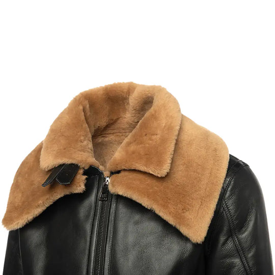 Side view of a black shearling bomber jacket with a tan shearling collar and leather sleeves.