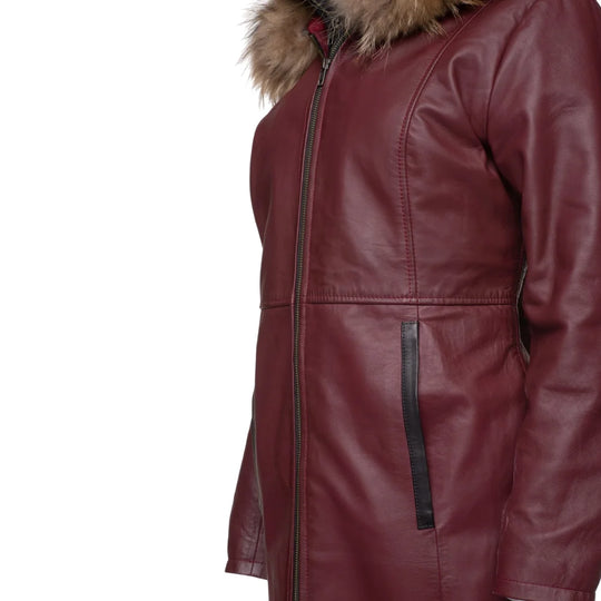 A close-up side view of a burgundy leather jacket showing the fine stitching, the texture of the fox fur collar, and the black leather piping on the vertical side pocket with white background.