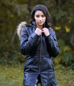 Woman Side profile in Jazmyn's long winter coat, emphasizing the thick fox fur hood and the protective longline fit in a forest setting.