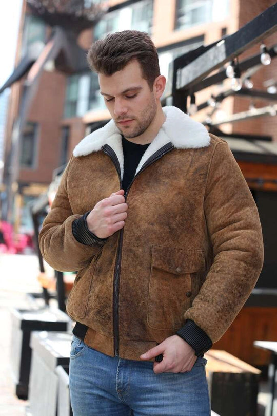 Man wearing Lucian's distressed brown A2 Bomber shearling jacket with white fur lining outdoors.