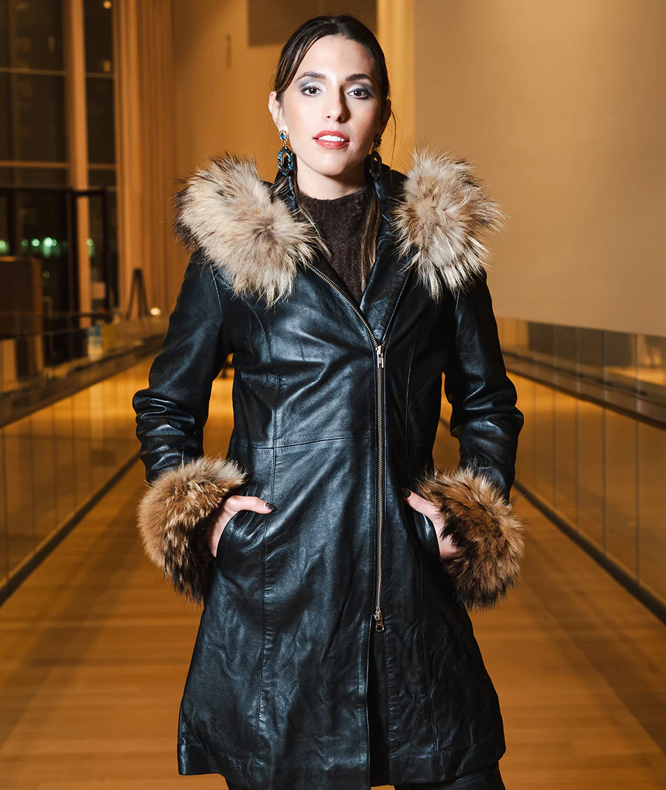Woman wearing a black leather coat with fur trim in an indoor setting