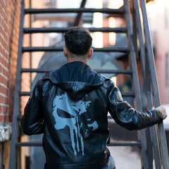 A back side of the male model wearing the Punisher's leather motorcycle jacket while standing next to a cruiser bike, showcasing the jacket's fit and aggressive style.