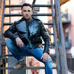 A male model wearing the Punisher's leather motorcycle jacket while standing next to a cruiser bike, showcasing the jacket's fit and aggressive style.