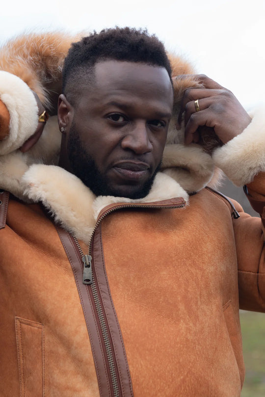 Man wearing a Cognac shearling aviator leather jacket with fur lining, standing outdoors.