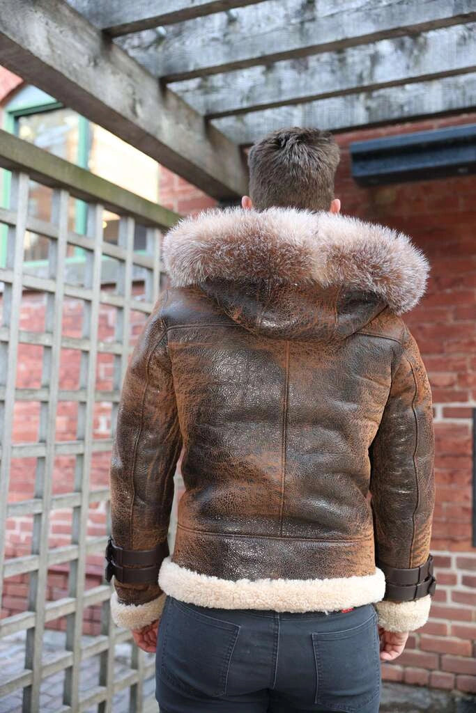 Person wearing Rocco vintage brown aviator shearling jacket with fur trim, standing outdoors.