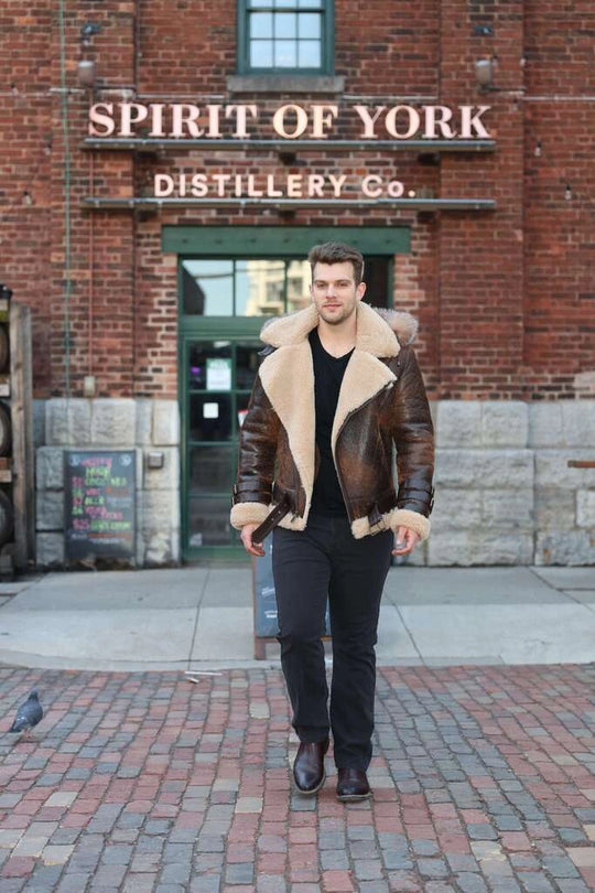 Man in Rocco vintage brown aviator shearling jacket walking in front of the Spirit of York Distillery Co. building.