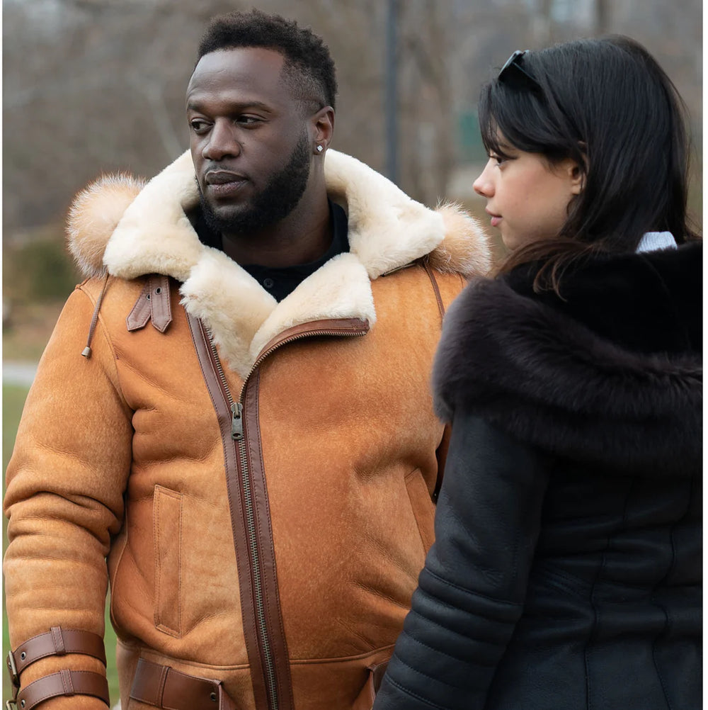 Two people wearing winter Shearling jacket and coat in an outdoor winter setting with a blurred background