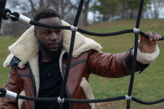 Man wearing a Terry Gretzky Vintage Oxblood bomber jacket with double collar with white fur lining on a playground.