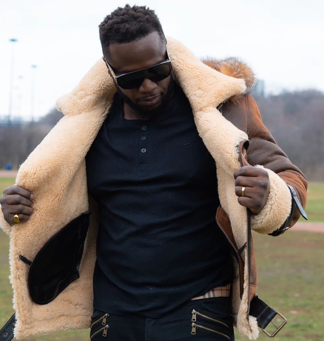 A Man posing and showcasing interior of a brown shearling aviator jacket in an outdoor setting.